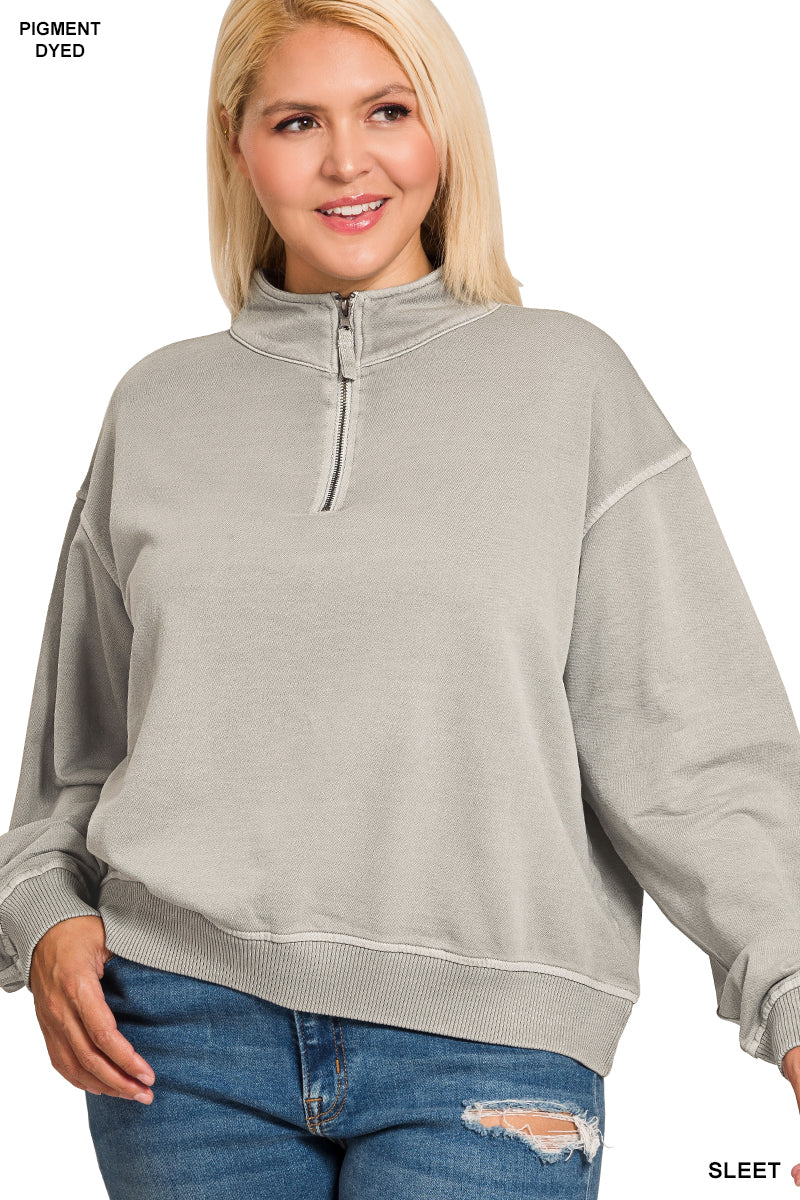 Woman wearing a gray half-zip sweatshirt and blue jeans on a white background