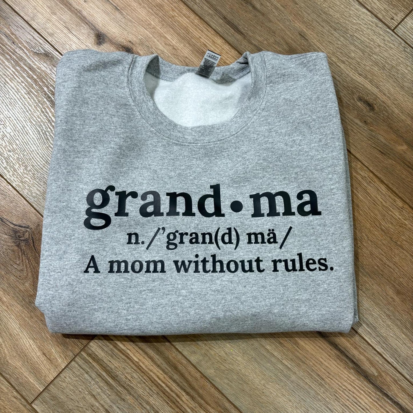 Folded gray sweatshirt with text on a wooden floor
