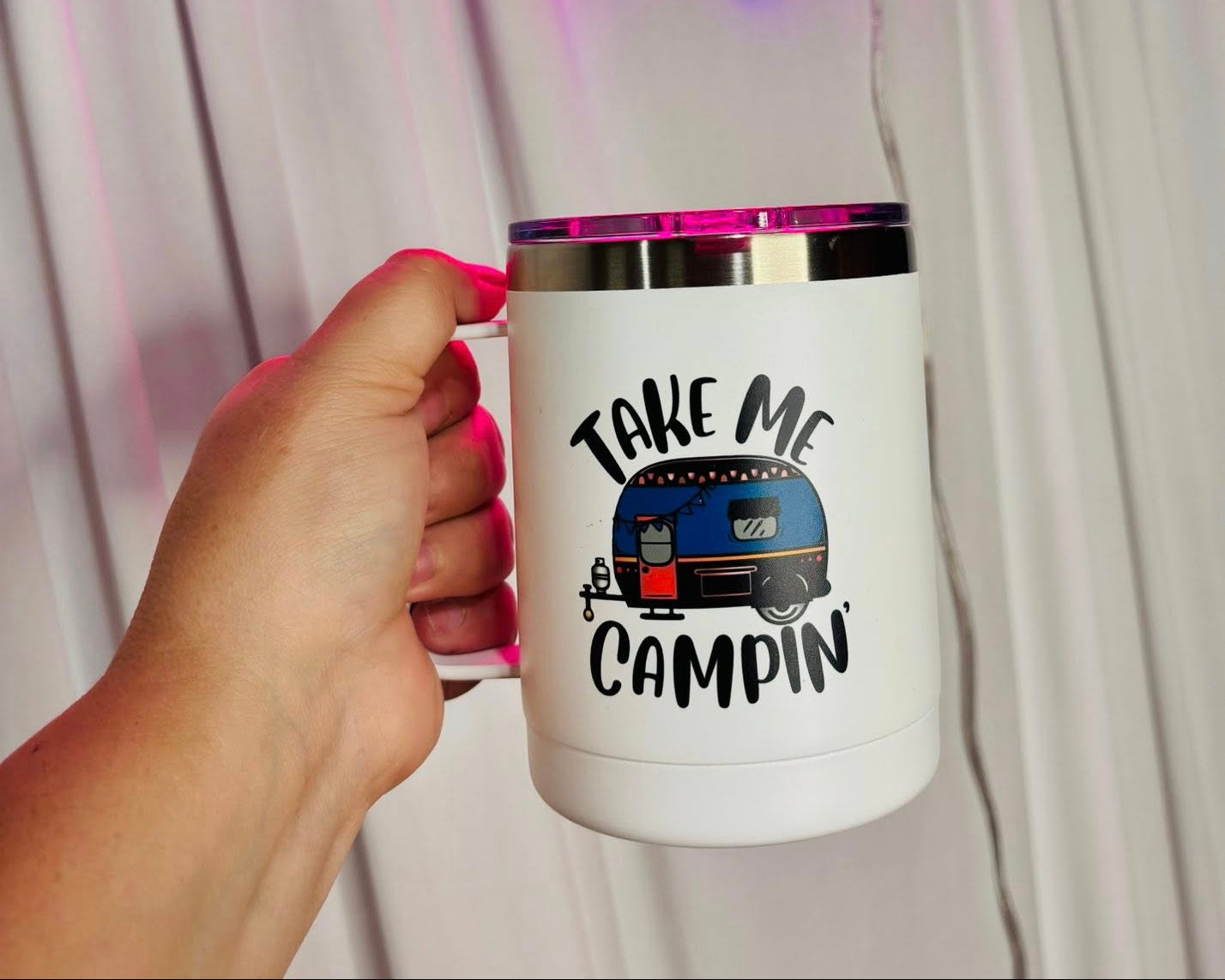 Neon sign with 'Come In Sweet & Apparel' and a mug with 'Take Me Camping' design.