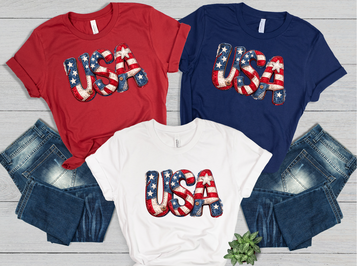 Three t-shirts with 'USA' design on a wooden surface with jeans.