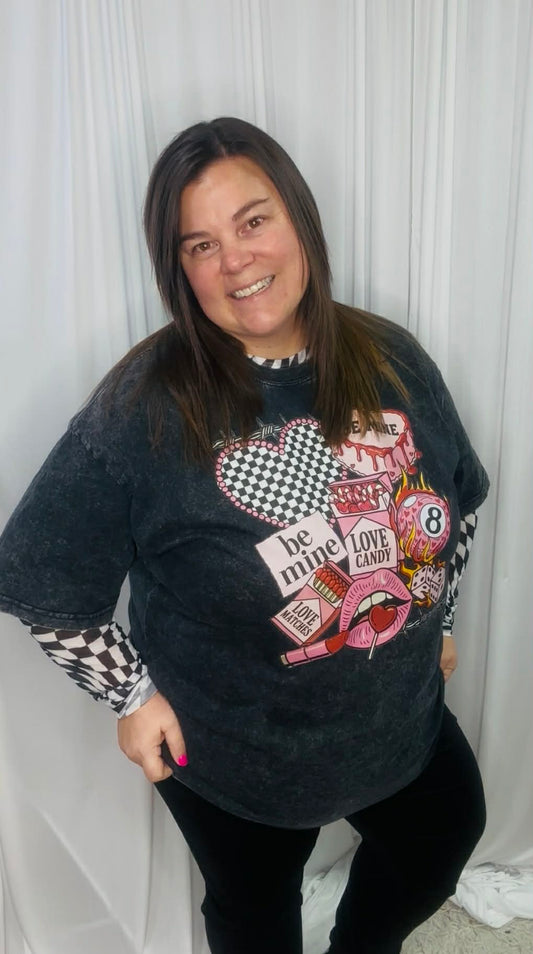 Woman wearing a black oversized sweater with colorful graphic designs against a white curtain background