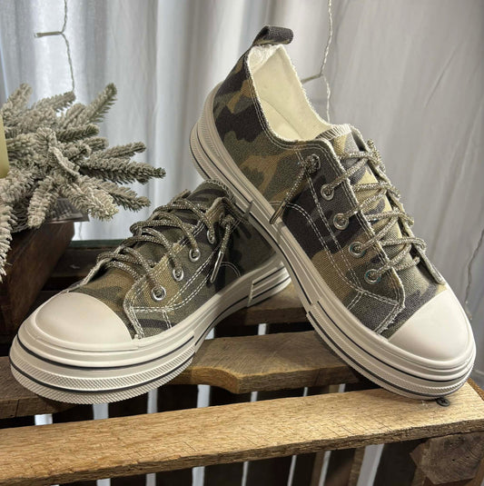 Camouflage sneakers with white soles on a wooden surface