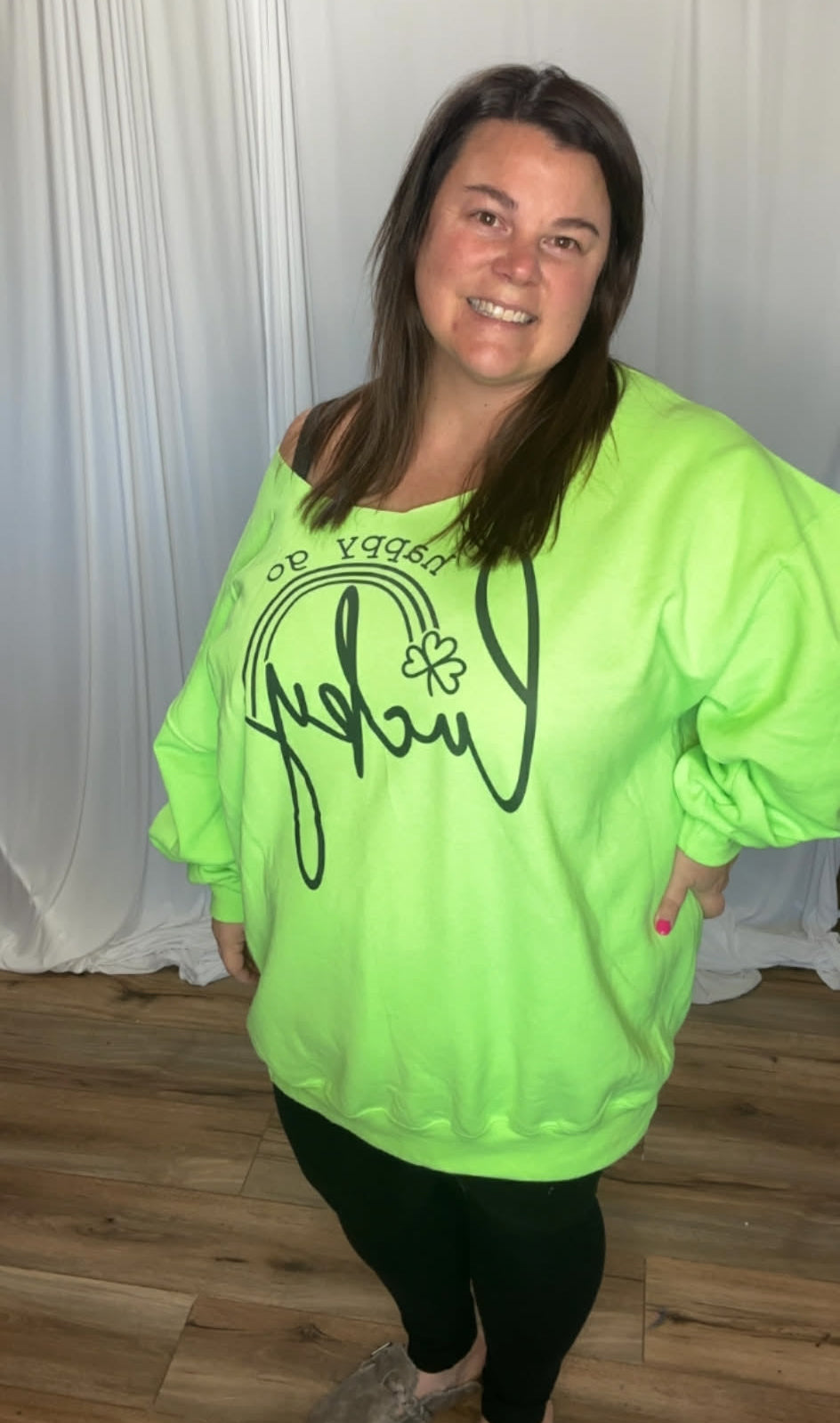 Person wearing a bright green sweatshirt with text, standing indoors.