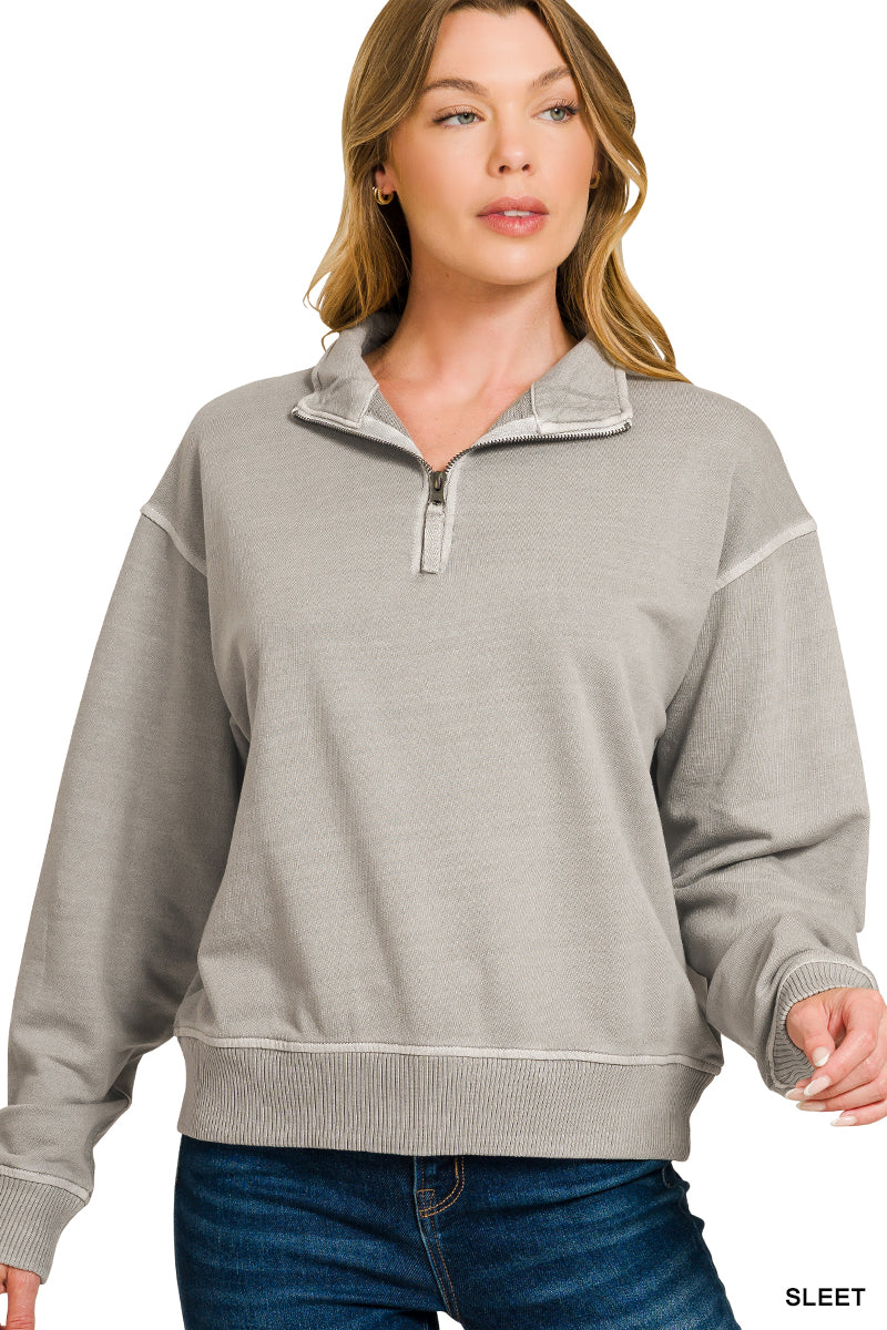 Woman wearing a gray half-zip sweatshirt on a white background