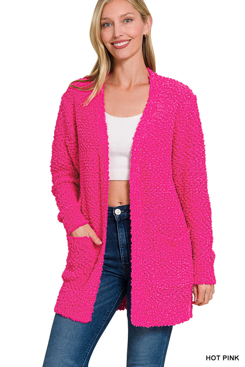 Woman wearing a hot pink cardigan over a white top and blue jeans on a white background