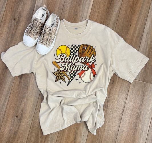 Beige t-shirt with 'Ballpark Mama' graphic on a wooden floor with leopard print sneakers.