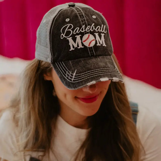 Person wearing a 'Baseball Mom' cap with a pink curtain background