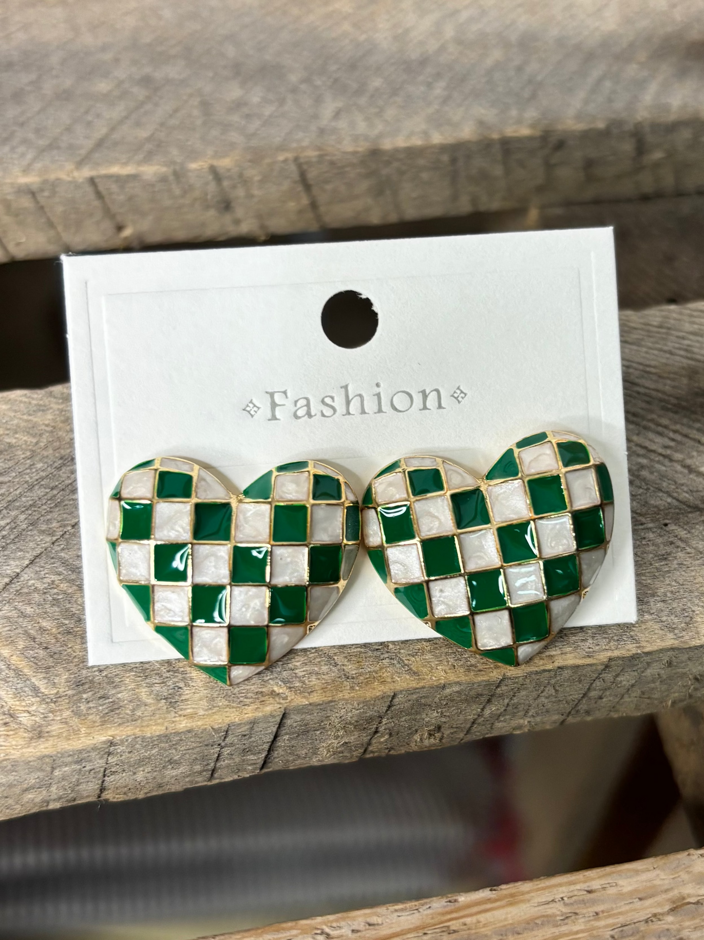 Checkered heart-shaped earrings on a 'Fashion' branded card, placed on a wooden surface.