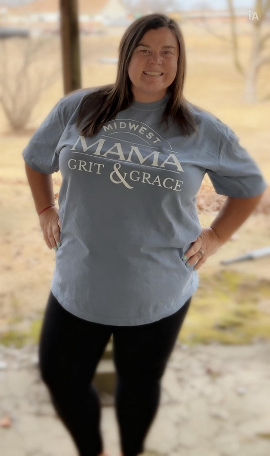 Person wearing a gray t-shirt with text standing outdoors.