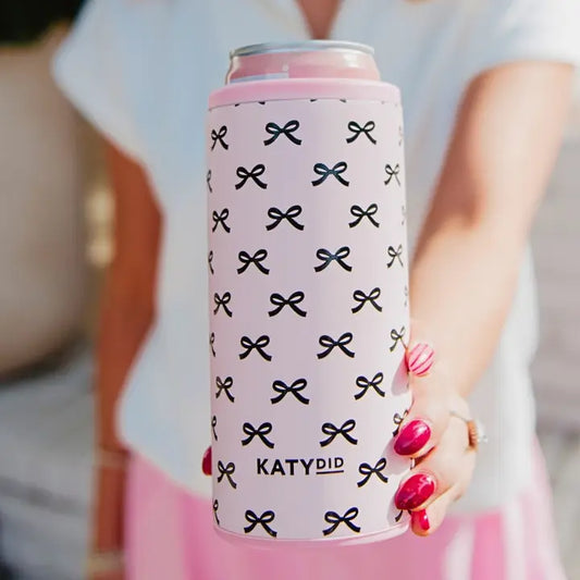 Can with pink and black bow pattern held by a person with pink nails.