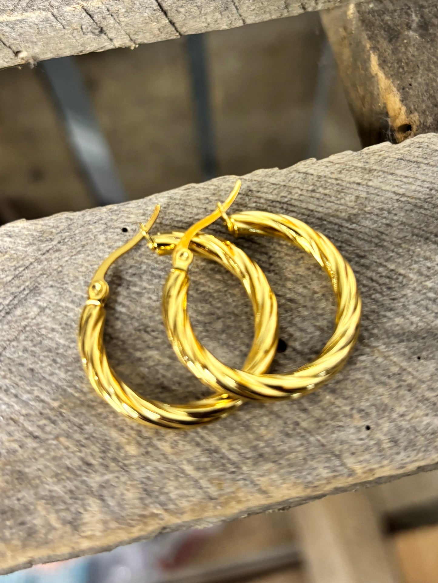 Gold hoop earrings on a wooden surface