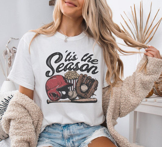 Woman wearing a white t-shirt with sports-themed graphic and text 'It's the Season'.