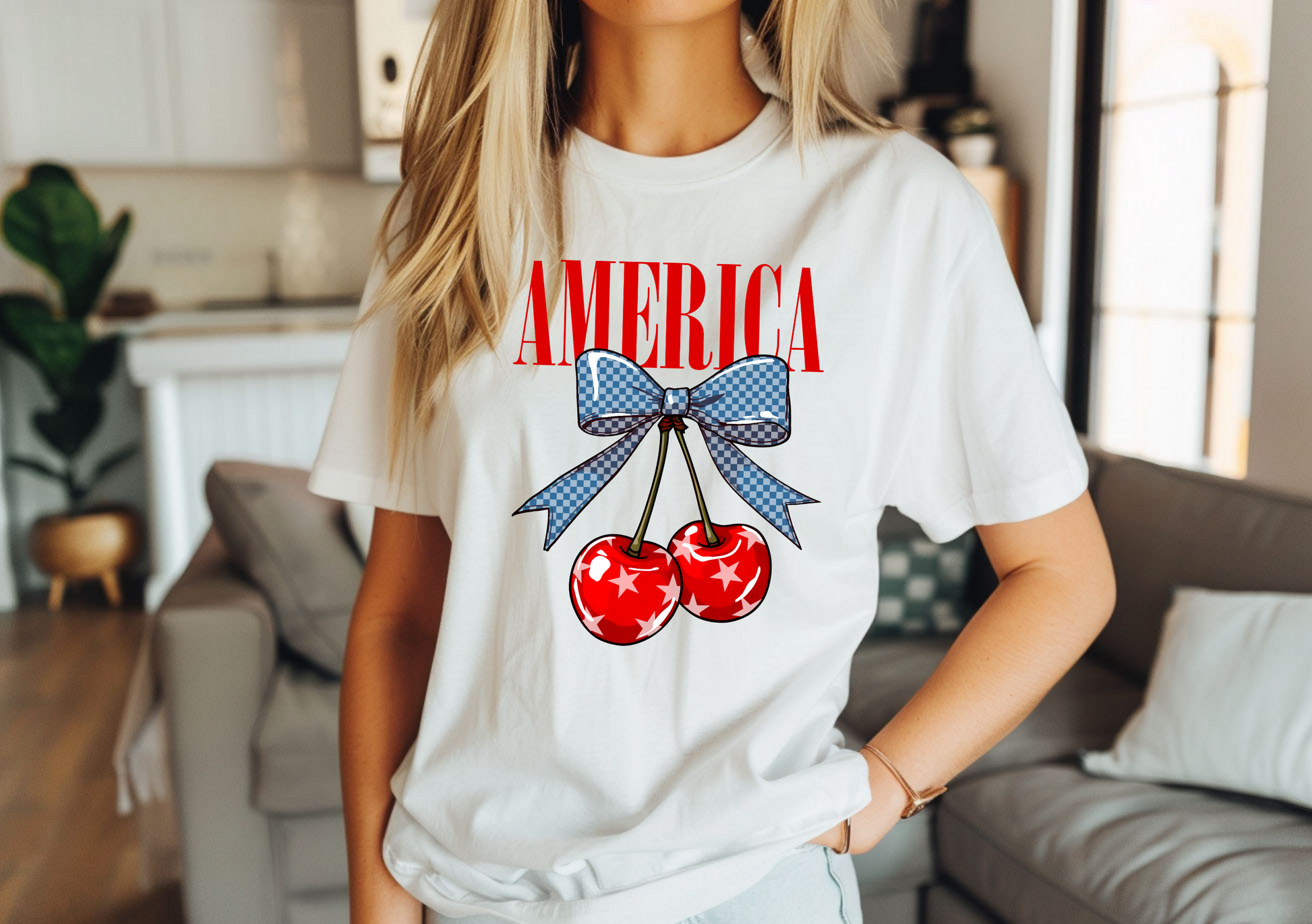 Person wearing a white t-shirt with 'AMERICA' and cherry design in a living room.